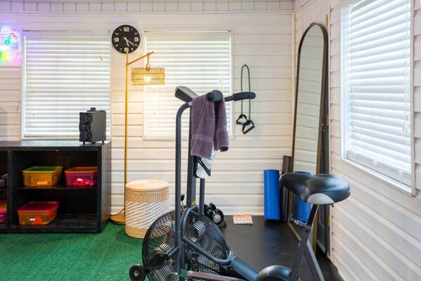 A home gym with exercise equipment, a clock, and storage shelves.