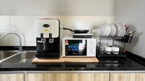 A kitchen with a coffee maker, microwave, and a dish rack. - RiverView 8Pax 3Br in KBtown PS4, Netflix A-1-2 (Kota Bharu)