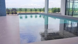 A swimming pool with clear water, surrounded by a tiled deck and large windows offering a view of greenery. - RiverView 8Pax 3Br in KBtown PS4, Netflix A-1-2 (Kota Bharu)