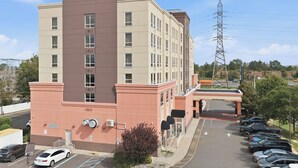 A multi-story hotel with a parking lot in front. - Near NYC • Inviting Double Suite • Sleeps 4 • Prime Location (Carteret)