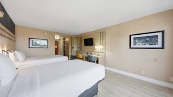 A hotel room with a large bed, a desk, a chair, a television, and two framed pictures on the wall.