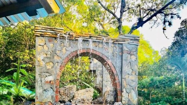 A stone archway leading to a small waterfall over a pool. - The Dock Resort  (Roatan)