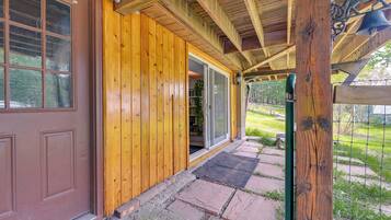 A wooden exterior with a brown door and a glass door leading to a covered porch.
