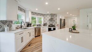 Een moderne keuken met witte kastjes, een centraal eiland en een decoratieve spatwand.