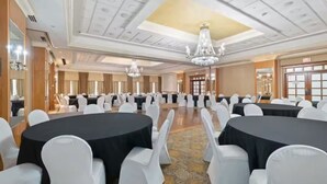 A banquet hall with round tables, white chairs, chandeliers, and a patterned carpet. - Near NYC • Tranquil Double Suite • Sleeps 4 • Prime Location (Carteret)