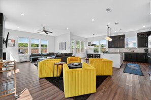A modern living room with a sofa set, yellow ottomans, and a dining table.