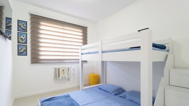 A bunk bed room with a window, a wall socket, and framed pictures. - Apto c Piscina e Quadras no Recreio (Rio de Janeiro)