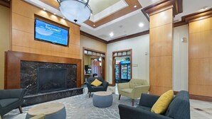 A lobby with a large screen displaying 'fortuneoff', a fireplace, comfortable seating, and a patterned floor.