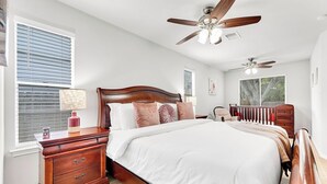 A bedroom with a wooden bed, two nightstands, a dresser, and a ceiling fan.