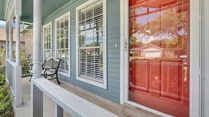 A house with a porch, a red door, and a bench.