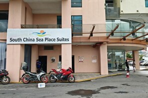 A hotel entrance with a sign for 'South China Sea Place Suites,' a covered walkway, and motorcycles parked outside. - Meetsuite at Kota Kinabalu (Kota Kinabalu)