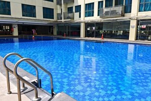 A swimming pool with a tiled floor, surrounded by a building with multiple windows and balconies. - Meetsuite at Kota Kinabalu (Kota Kinabalu)
