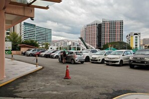A parking lot with cars, a traffic cone, and modern buildings in the background. - Meetsuite at Kota Kinabalu (Kota Kinabalu)
