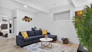 A modern living room with a grey sofa, a round coffee table, and a patterned rug. - Welcoming and Spacious 1-bedroom unit in Edmonton (Edmonton)