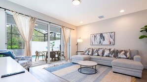 Un salon moderne comprenant un canapé, une table basse et un coin repas avec des chaises et une table.