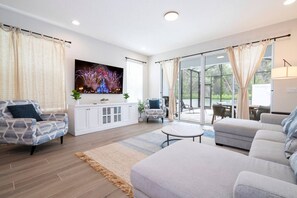 A modern living room with a flat-screen TV, two sofas, a coffee table, and a cabinet.