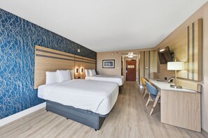 Ein Hotelzimmer mit einem großen Bett, einem Schreibtisch und einem Stuhl. Es befindet sich ein Spiegel und ein Bild an der Wand.