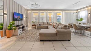 A modern living room with a sectional sofa, a dining table, and a TV. - Entire House Davenport ~ Pool ~ Resort Access (Davenport)