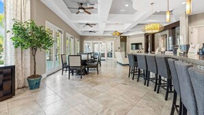 A spacious kitchen with modern appliances, a dining area with bar stools, and a large potted plant. - Entire House Davenport ~ Pool ~ Resort Access (Davenport)