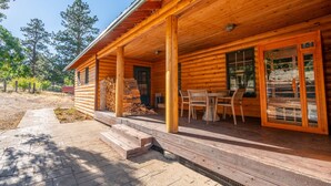 A wooden cabin with a porch, a dining table, and chairs. - Reverie Ranch @ Gold Mountain 136 Acre w/ Lakeview, Sauna, & Nat'l Forest Access (Milford)