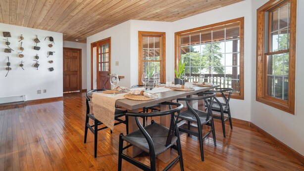 A dining area with a wooden ceiling, large windows, and a long table set for six. - Reverie Ranch @ Gold Mountain 136 Acre w/ Lakeview, Sauna, & Nat'l Forest Access (Milford)