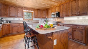 A kitchen with wooden cabinets, a central island with a cutting board, and a window. - Reverie Ranch @ Gold Mountain 136 Acre w/ Lakeview, Sauna, & Nat'l Forest Access (Milford)