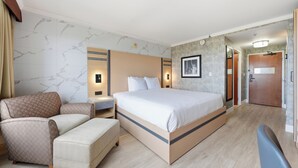 Une chambre d’hôtel avec un lit, une chaise, un bureau et une armoire.