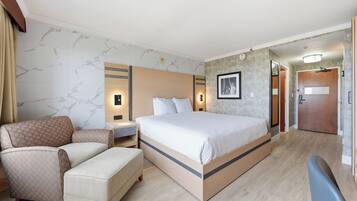 A hotel room with a bed, a chair, a desk, and a wardrobe.
