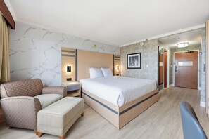 Une chambre d’hôtel avec un lit, une chaise, un bureau et une armoire.