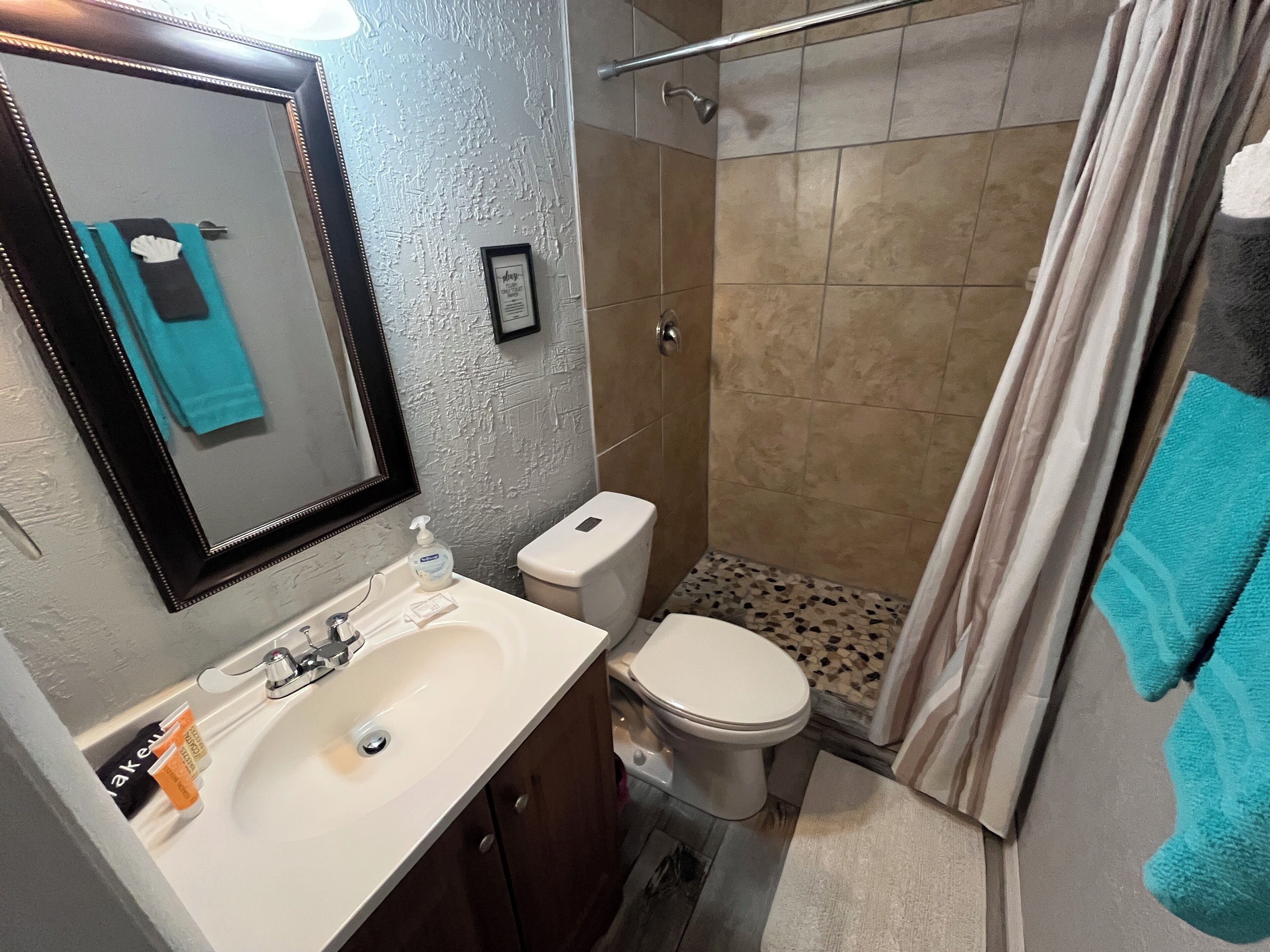 A bathroom with a sink, toilet, and shower.