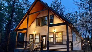 Eine Holzhütte mit verdeckter Veranda und einer Treppe zum Eingang.