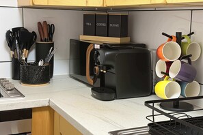 Eine Küche mit einer Kaffeemaschine, einem Becherhalter und einem Besteckhalter.