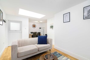 Ein modernes Wohnzimmer mit einer Couch, einem Couchtisch und einem Essbereich im Hintergrund.