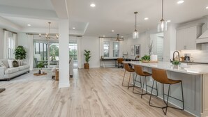 Una cocina moderna con una isla central, taburetes de bar e iluminación colgante.
