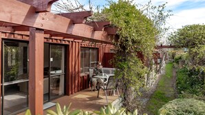 A wooden pergola with a glass door and a table with chairs outside a building. - Alpine Springs Motel | Unit 7 - HS51217 (Hanmer Springs)