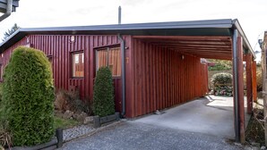 A red wooden building with a covered entrance and a number '7' sign. - Alpine Springs Motel | Unit 7 - HS51217 (Hanmer Springs)