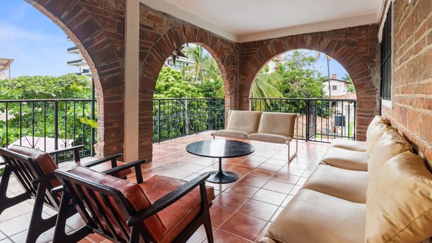 A covered patio with brick arches, a round table, and seating.