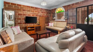 A living room with brick walls, a flat-screen TV, leather sofas, and a wooden coffee table.