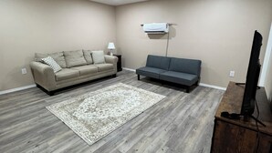 A living room with a beige sofa, a gray sofa, a wooden coffee table, a TV stand, and a patterned rug. - Country Nook farmhouse in San Benito (San Benito)