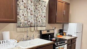A kitchen with wooden cabinets, a white sink, a stove, and a refrigerator. - Country Nook farmhouse in San Benito (San Benito)