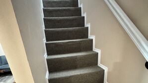 A carpeted staircase with white trim and a wooden floor. - Country Nook farmhouse in San Benito (San Benito)