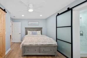 A bedroom with a bed, a ceiling fan, a sliding glass door, and a wooden door. - Sunset Retreat at the Lake | Sleeps 24 | Pool & Hot Tub (Sherrills Ford)