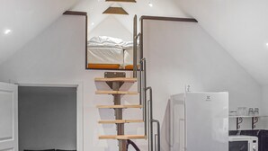 A compact kitchen with a white refrigerator, a microwave, and a wooden ladder leading to a loft bed. - Gorgeous home in Villands with lake view (Villands)