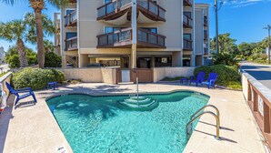 A swimming pool with blue chairs and a palm tree. - Beachside Bliss • Pool • Near Beach & Attractions (North Myrtle Beach)