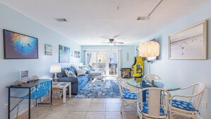 A living room with a sofa, coffee table, and chairs, a dining table with chairs, and a ceiling fan. - Beachside Bliss • Pool • Near Beach & Attractions (North Myrtle Beach)
