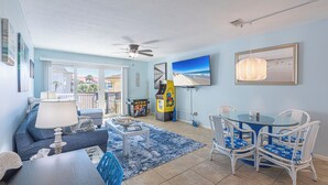 A living room with a sofa, coffee table, and chairs, a TV, and a ceiling fan. - Beachside Bliss • Pool • Near Beach & Attractions (North Myrtle Beach)