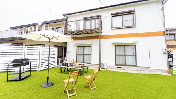 A two-story residential building with a balcony, a barbecue grill, a table with chairs, and a lawn. - Miraie Yokkaichi Aobacho (Yokkaichi)
