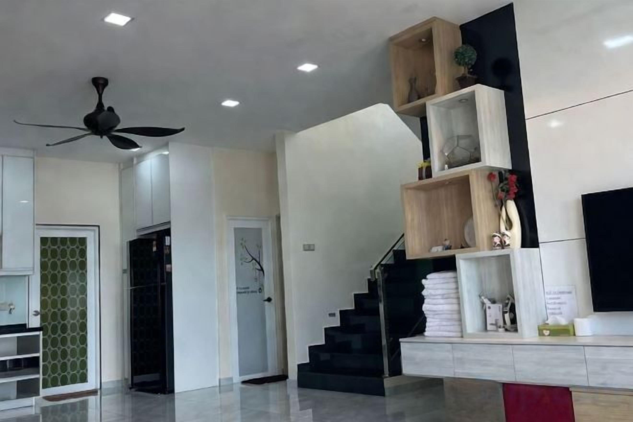 Een modern interieur met een trap, een plafondventilator en een flatscreen televisie aan de muur.