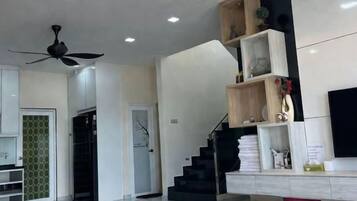 Een modern interieur met een trap, een plafondventilator en een flatscreen televisie aan de muur.