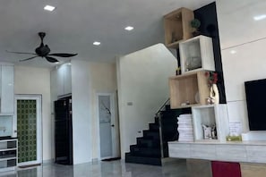 Ein modernes Interieur mit Treppe, Deckenventilator und flachbildschirm-Fernseher an der Wand.